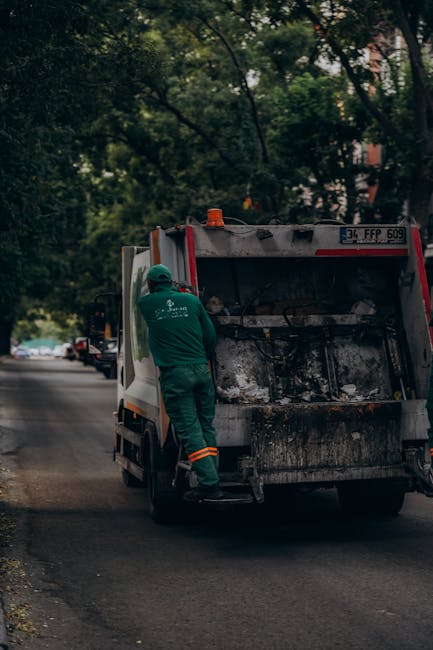 A large collection of mixed waste and rubbish, including black and clear plastic bags, flattened cardboard boxes, paper and cardboard packaging, and miscellaneous household items, all piled haphazardl